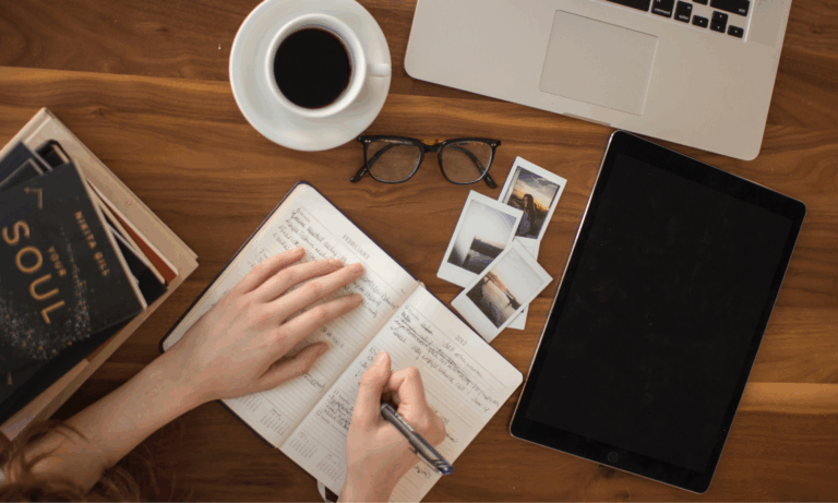 minimal writing workspace with coffee, notebook, and laptop on a wooden desk
