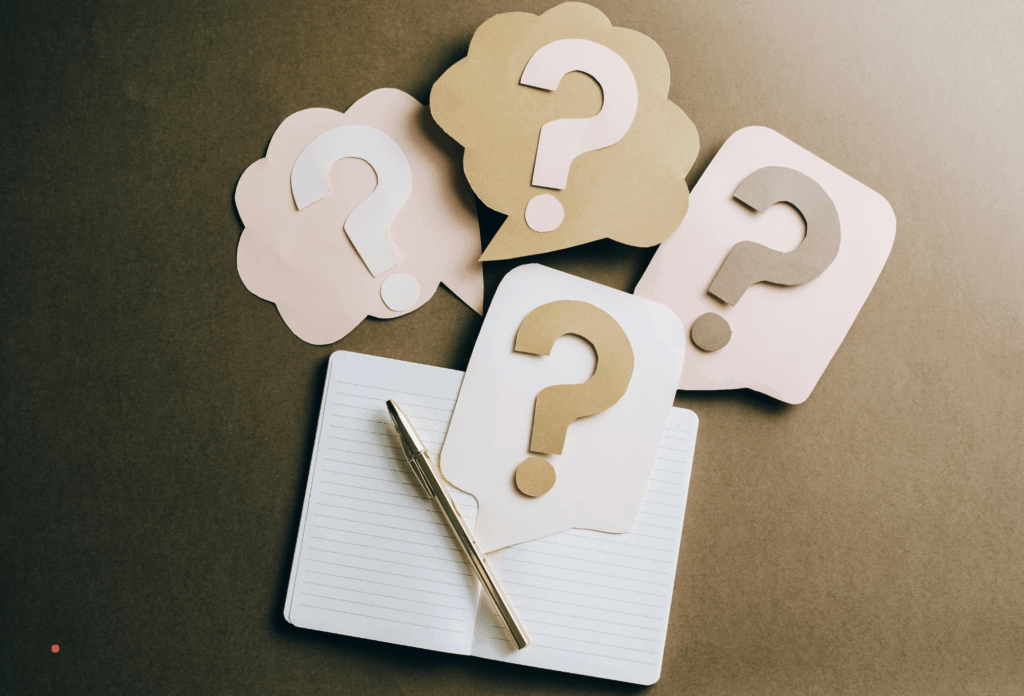 notebook and pen surrounded by question marks symbolizing uncertainty