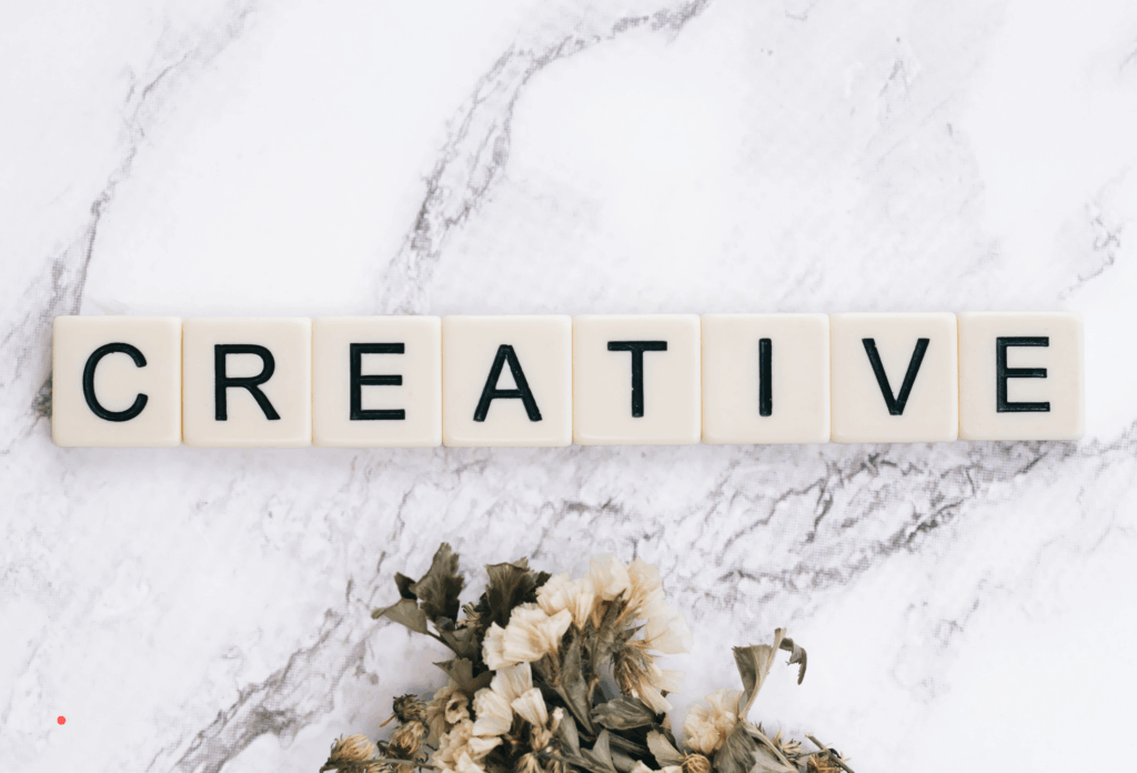 wooden letter tiles spelling “creative” on a light marble surface