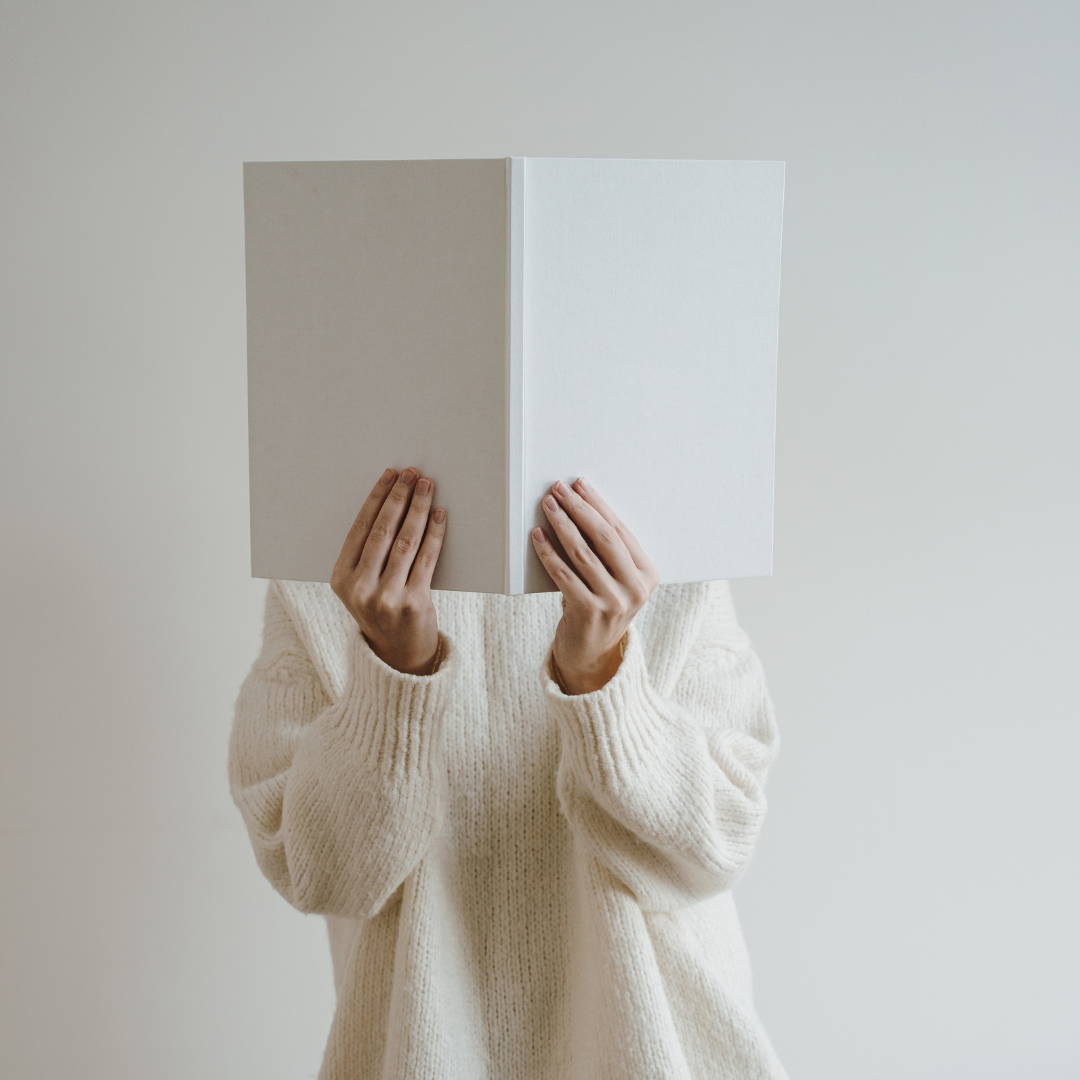 person holding an open book in front of their face symbolizing introspection