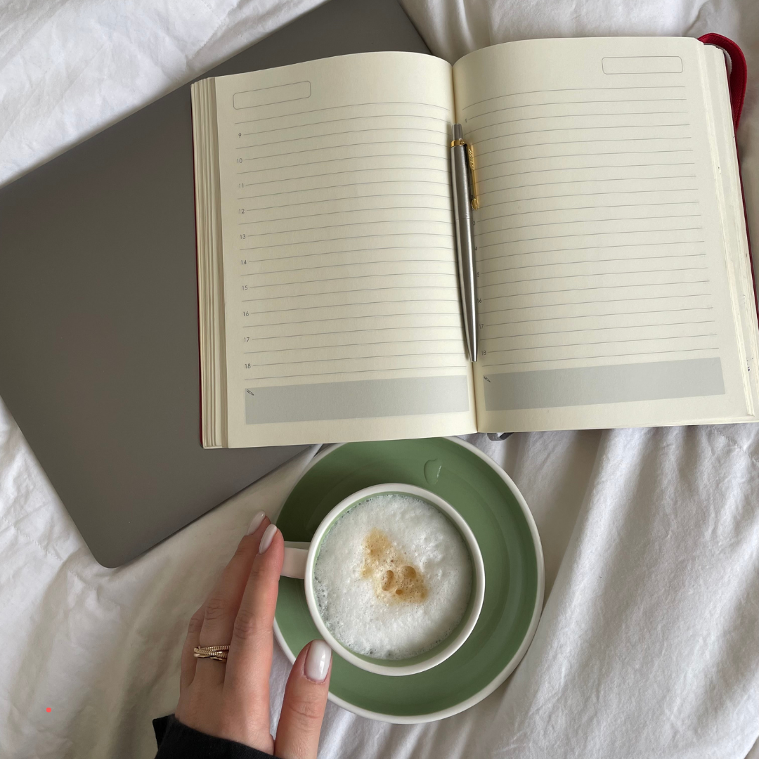 open journal and coffee cup on a bed during a quiet writing moment