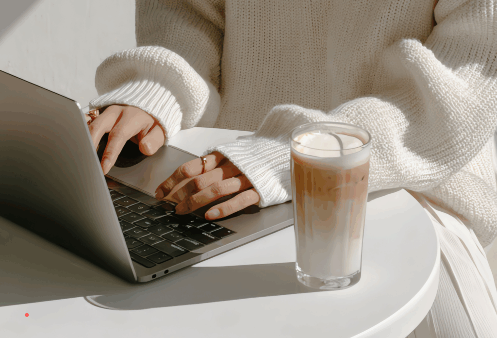 typing on a laptop beside a glass of coffee during a calm writing moment