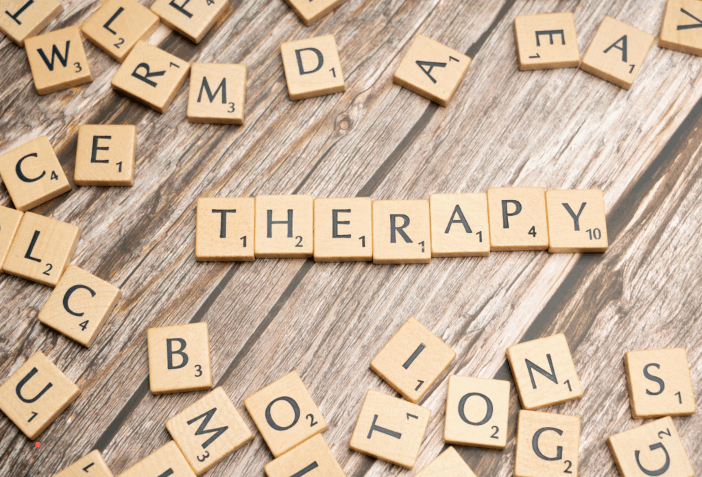 wooden letter tiles spelling “therapy” on a textured wooden background