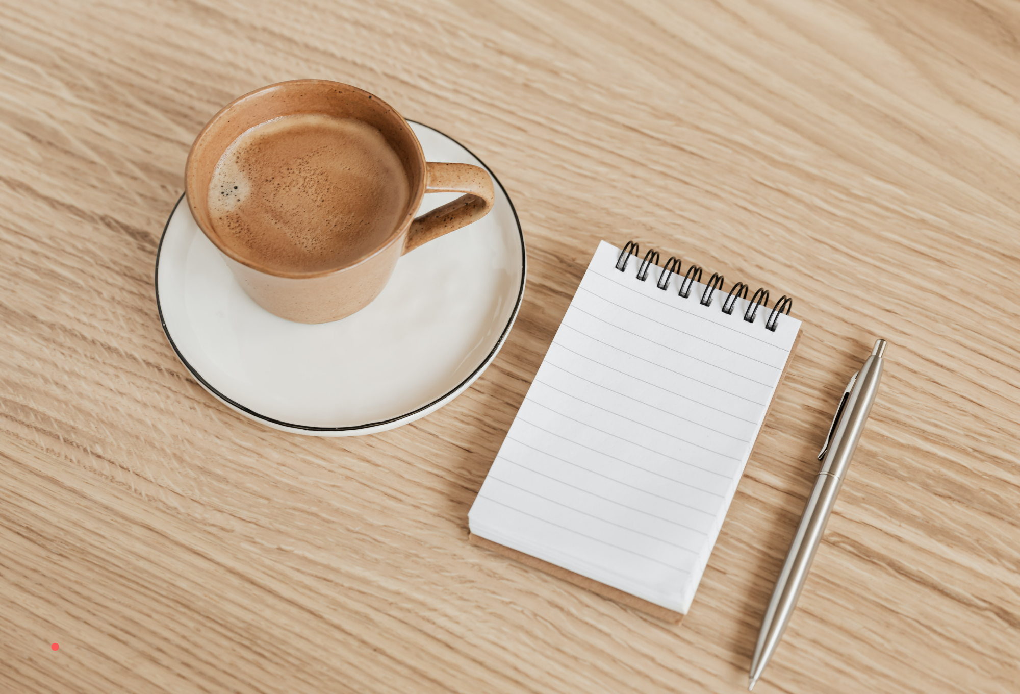 Notebook and pen beside a cup of coffee, creating a calm space for reflective journaling.