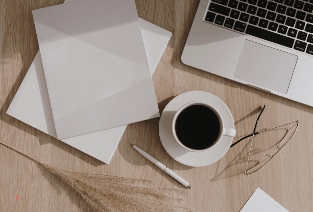 writing workspace with envelopes, coffee, pen, and laptop on a wooden desk