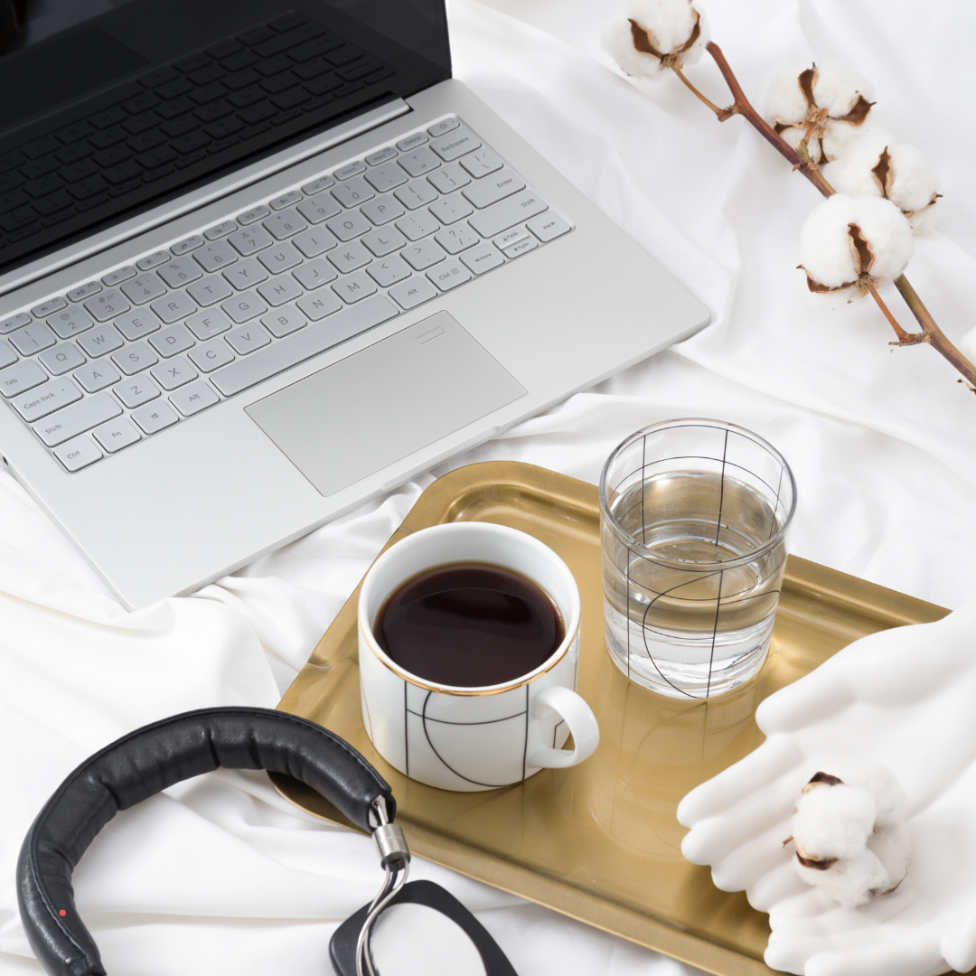Writing setup with a laptop, coffee, and headphones, creating a quiet journaling environment.