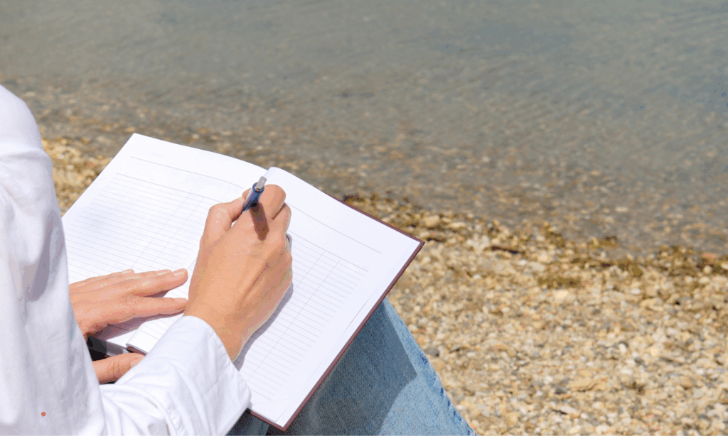 Writing in a notebook by the water for calm reflection.