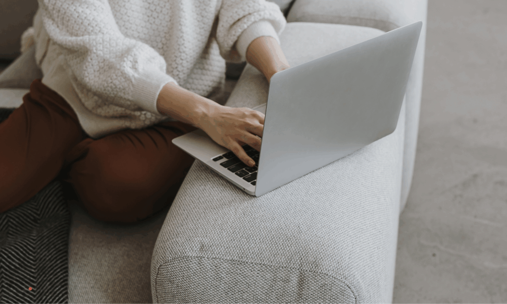 Person writing on a laptop in a calm, cozy home setting.