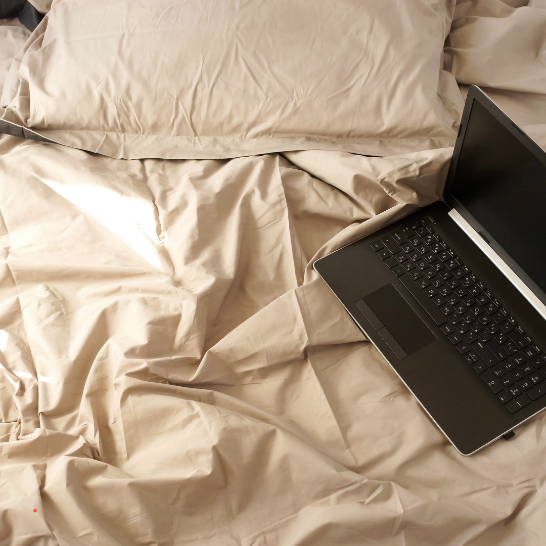 Laptop and notebook placed on an unmade bed, representing flexible and intuitive emotional writing at home