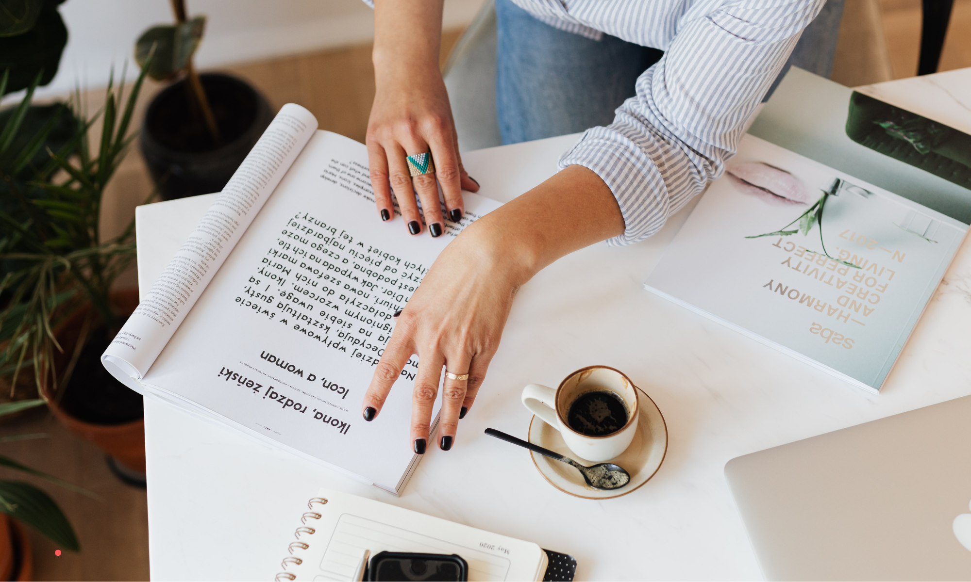 Person reviewing handwritten notes and journaling prompts at a desk with a cup of coffee.