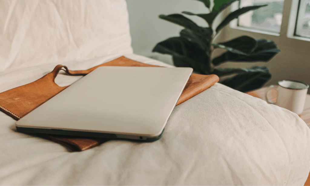Laptop resting on a bed in a peaceful home setting, representing gentle writing and personal reflection.