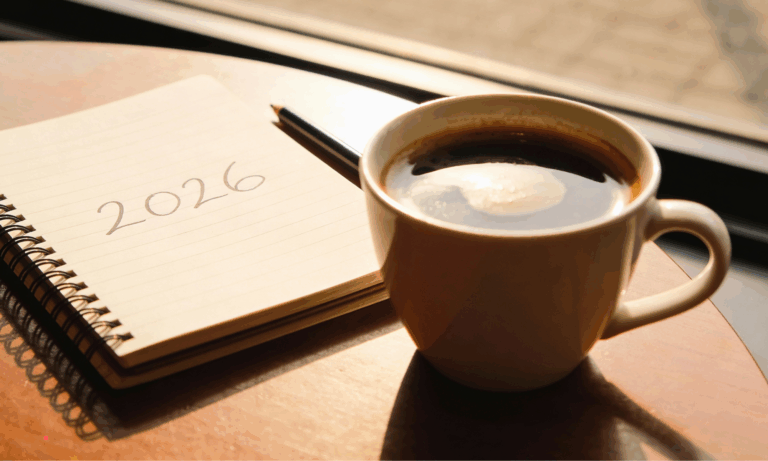 Journal prompts for emotional burnout written in a notebook beside a cup of coffee on a wooden desk.