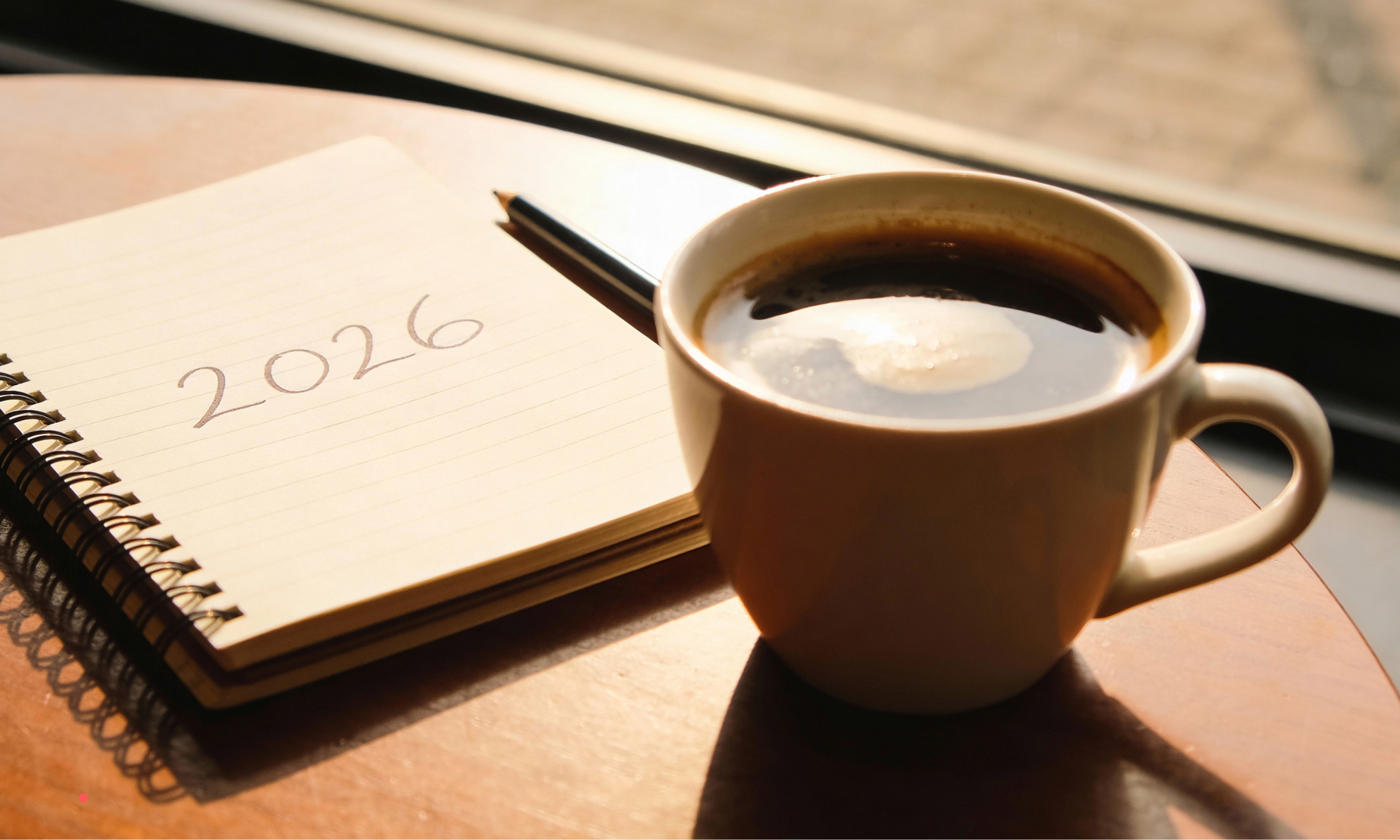 Journal prompts for emotional burnout written in a notebook beside a cup of coffee on a wooden desk.