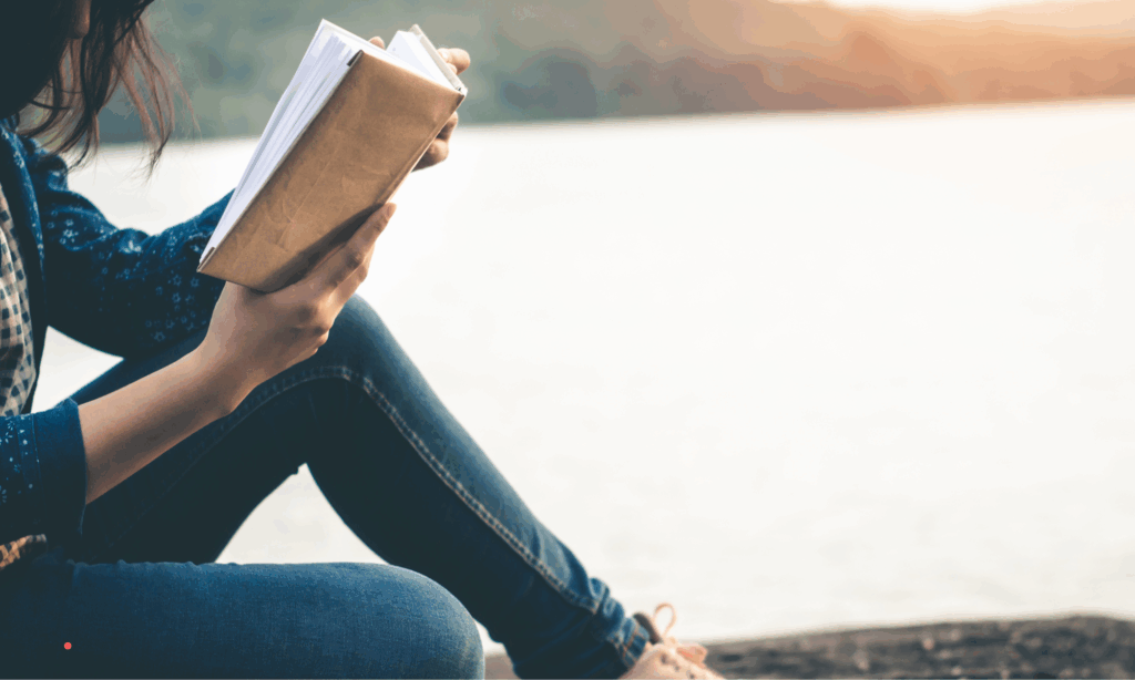 Quiet outdoor moment with a journal by the water, reflecting on thoughts and unspoken feelings.