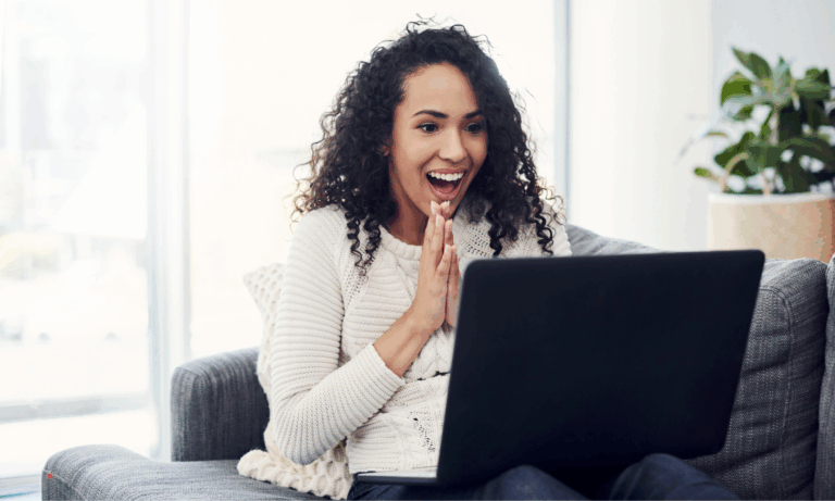 woman reacting emotionally while writing or reading a personal story on laptop